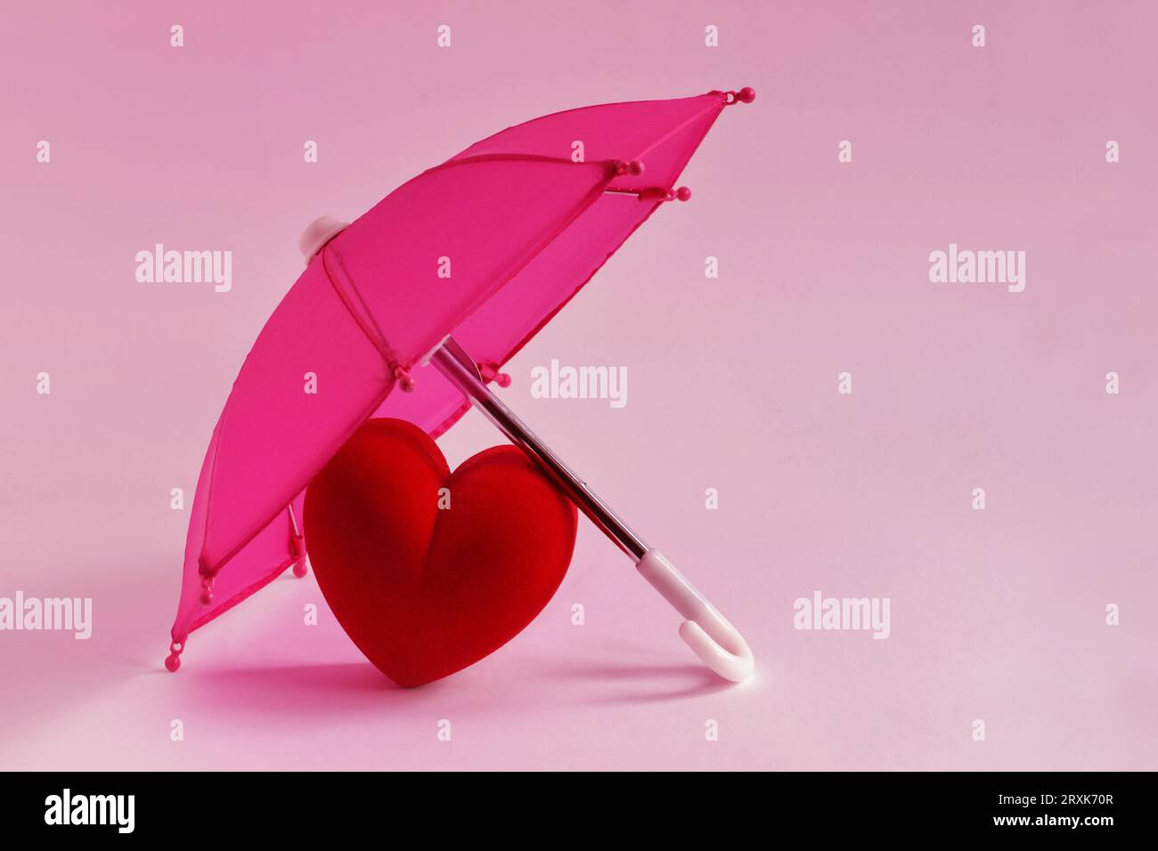 Herz unter rosafarbenem Schirm - Liebe und Schutzkonzept Stockfoto