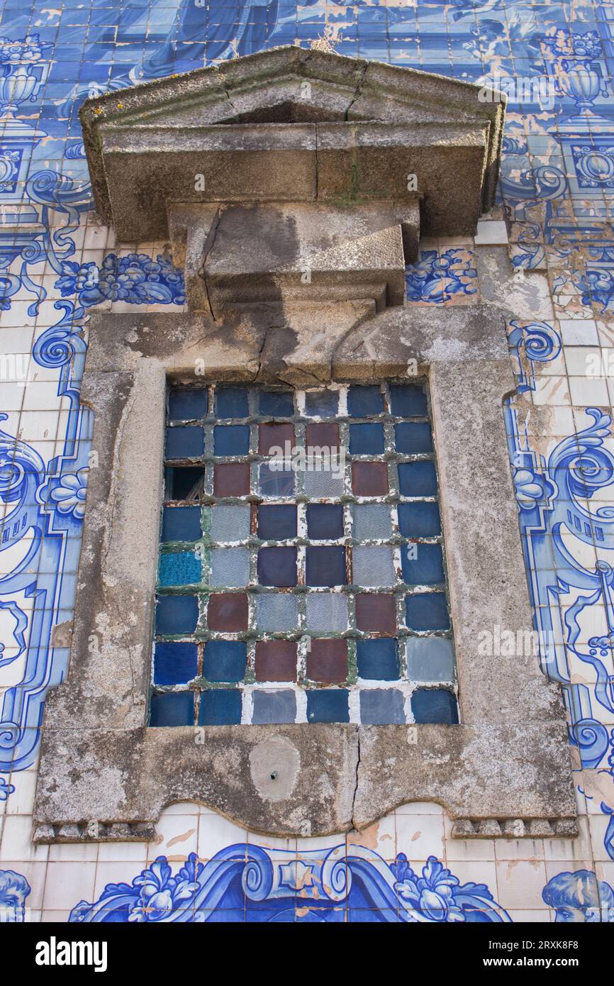 Buntglasfenster und Azulejo-Fliesen an der Kirchenfassade in Porto, Portugal. Traditionelle portugiesische Außendekoration. Alte Kirchendekoration. Stockfoto