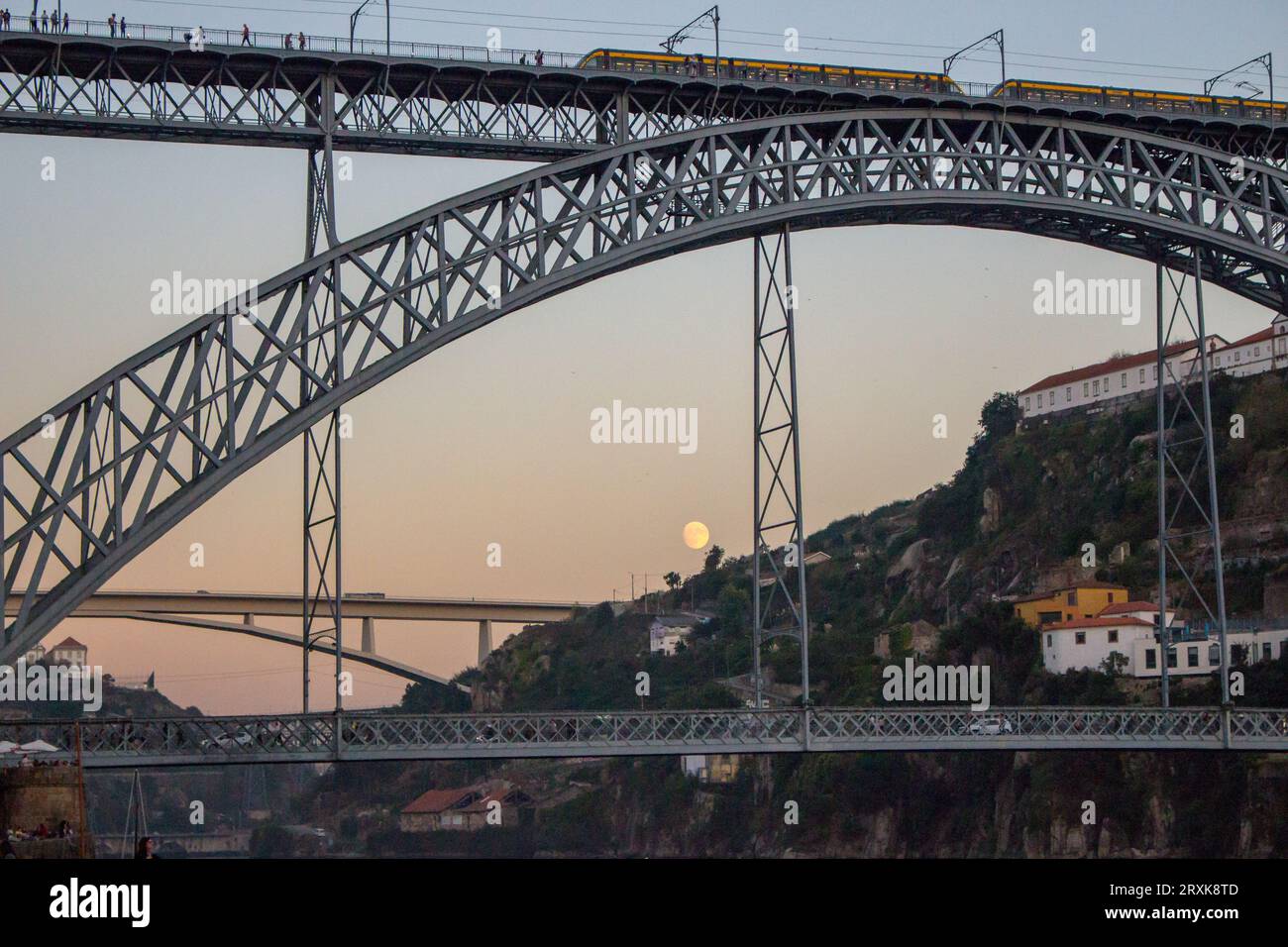 Die berühmte Porto Brücke Ponte Luis am Abend mit Blick von unten. Porto-Brücke in der Dämmerung mit Mond im Hintergrund. Portugiesischer Fluss Douro mit U-Bahn-Brücke. Stockfoto