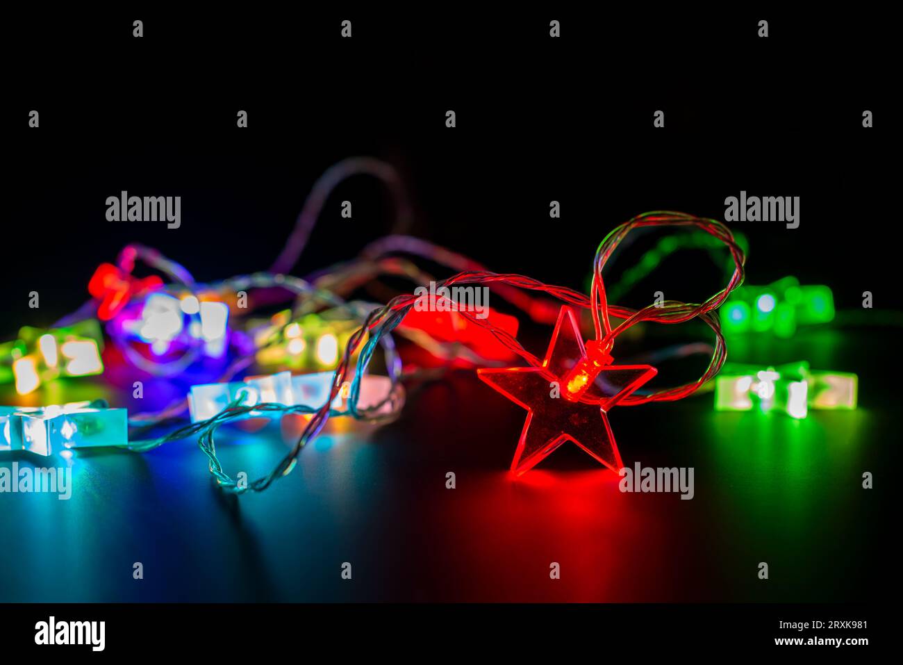 Nahaufnahme von bunten elektrischen weihnachtsbeleuchtung Girlanden in Form von Sternen, moderne Ferienwohnung Dekor auf schwarz Stockfoto