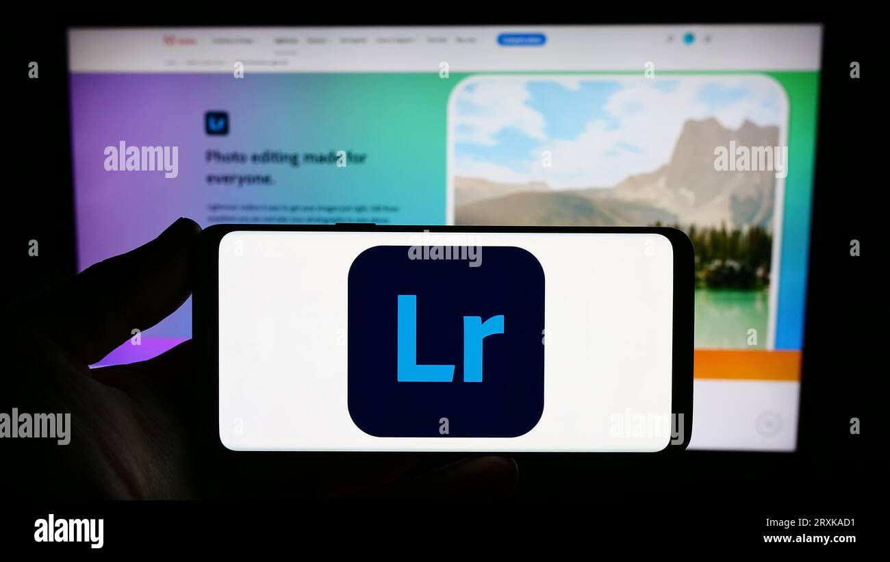 Person, die ein Smartphone mit dem Logo der Bildverarbeitungssoftware Adobe Lightroom auf dem Bildschirm vor der Website hält. Konzentrieren Sie sich auf das Display des Telefons. Stockfoto