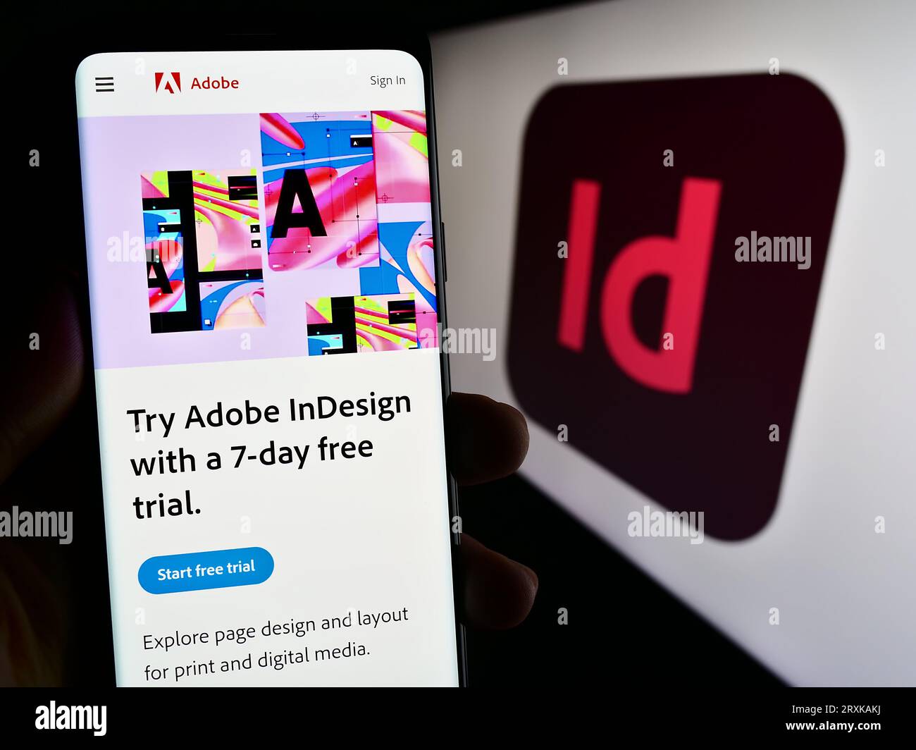 Person, die ein Smartphone mit Webseite der Desktop-Publishing-Software Adobe InDesign auf dem Bildschirm mit Logo hält. Konzentrieren Sie sich auf die Mitte der Telefonanzeige. Stockfoto
