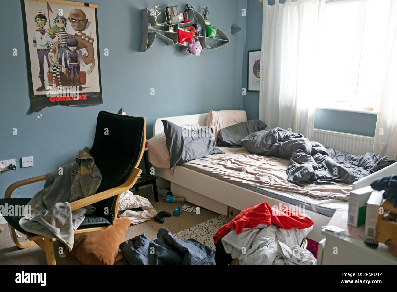 Unordentliches Schlafzimmer mit Teenager-Jungen und ungebastelten Bettwäsche Gorillaz-Posterstuhl grau-blaue Wände Wandfarbe bemalt Großbritannien Großbritannien 2023 KATHY DEWITT Stockfoto
