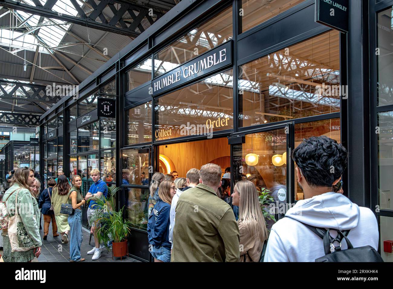 Leute, die Schlange stehen, um in das beliebte Dessertrestaurant Humble Crumble am Old Spitalfileds Market, London E1, zu kommen Stockfoto