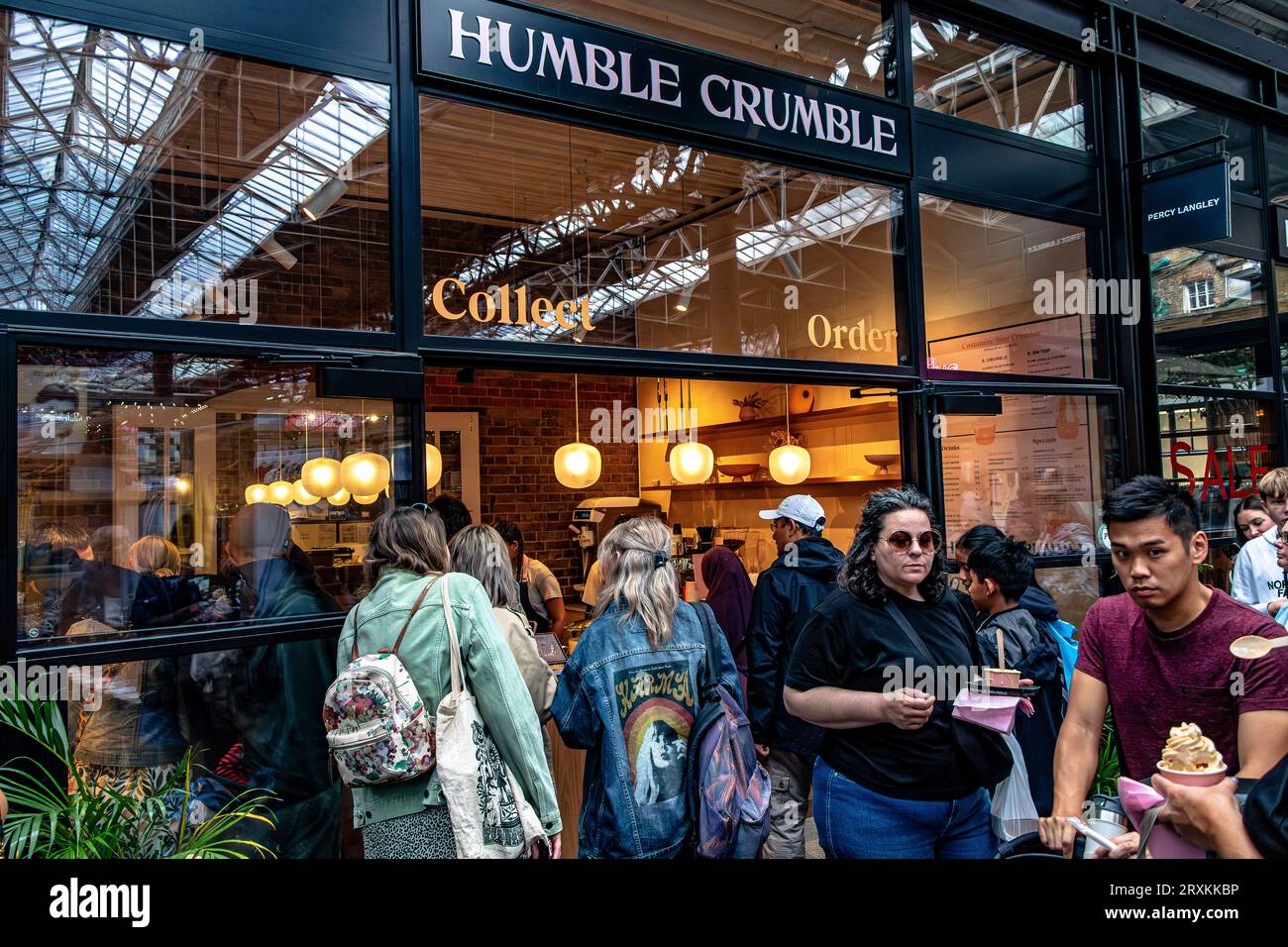 Leute, die Schlange stehen, um in das beliebte Dessertrestaurant Humble Crumble am Old Spitalfileds Market, London E1, zu kommen Stockfoto