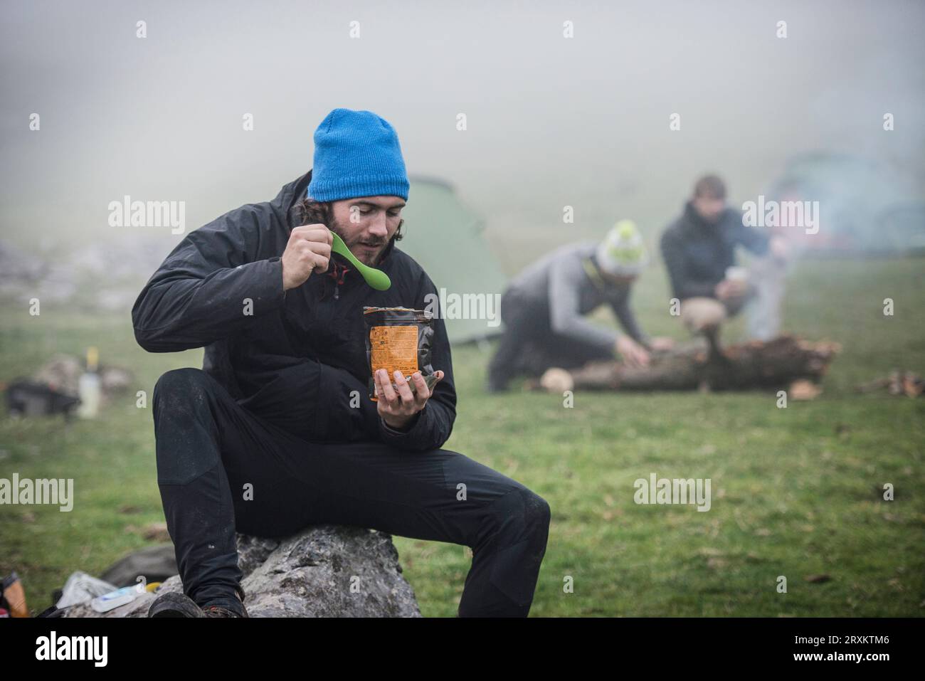 Junger Mann Essen aus der Tüte an nebligen Camp Stockfoto