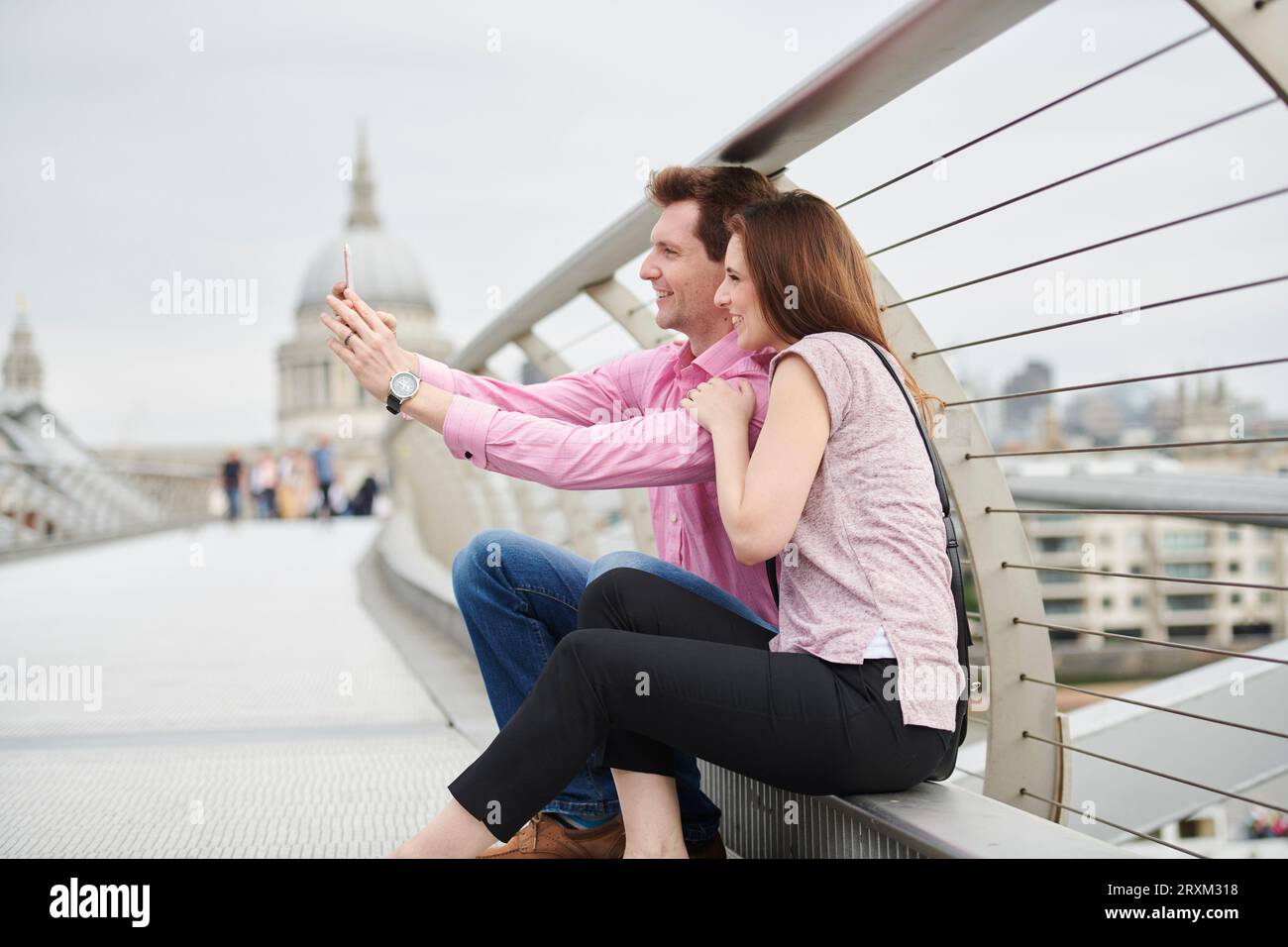 Mitte nach paar unter selfie über die Millennium Bridge in London. Stockfoto