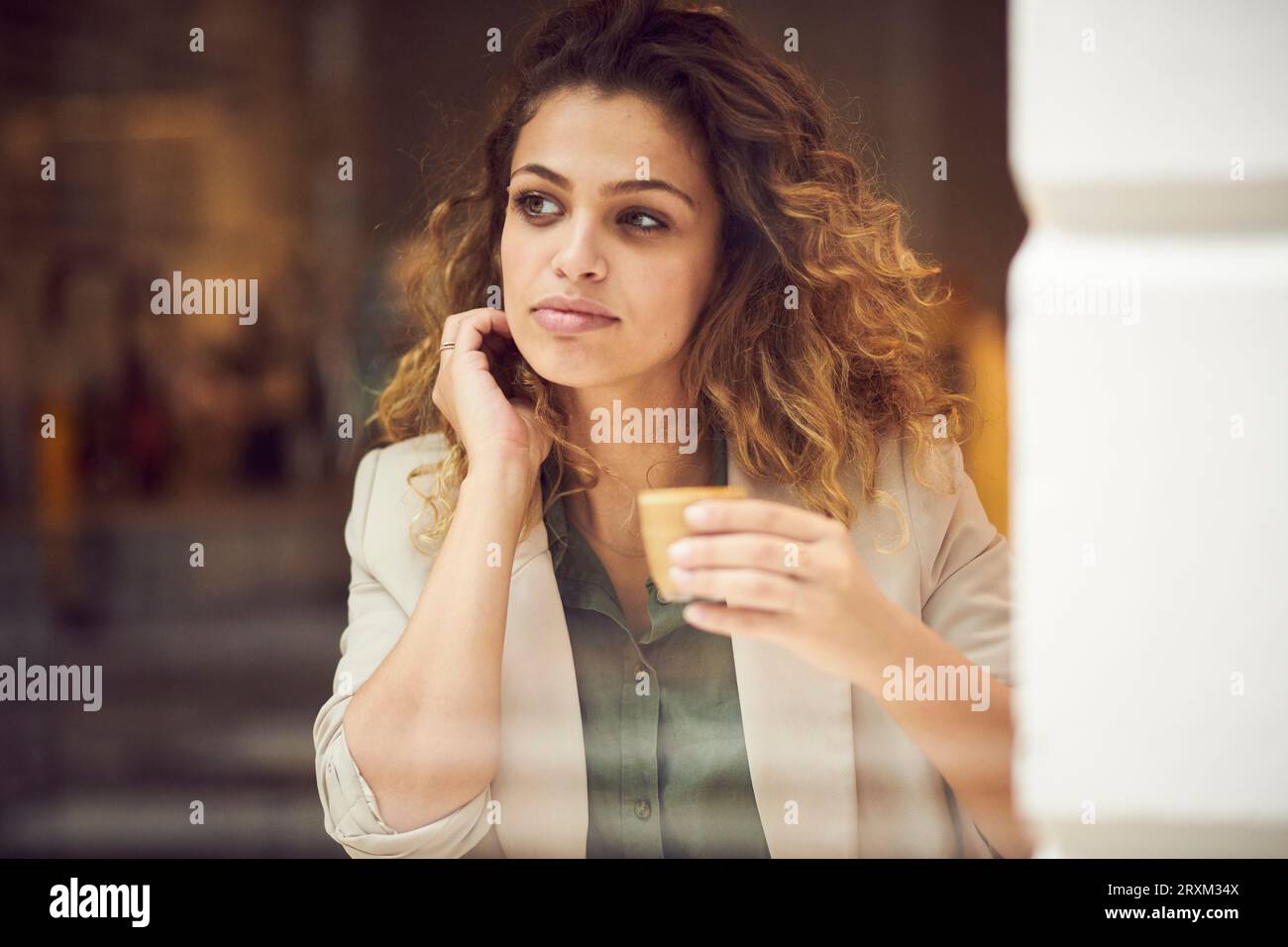 Junge Frau mit Tasse Kaffee hinter Fenster Cafe Stockfoto
