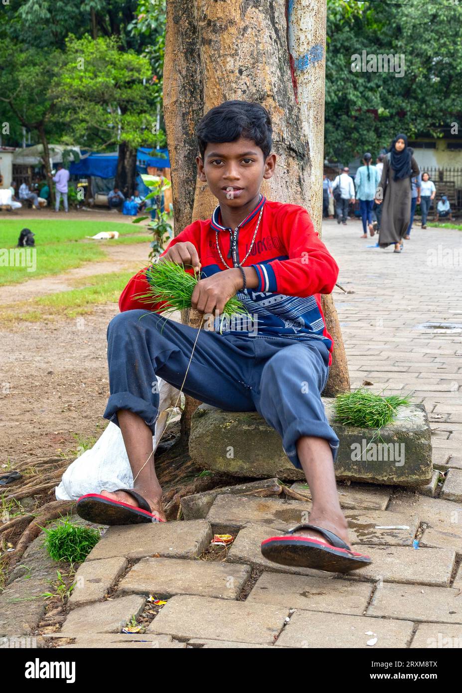 MUMBAI – 21. SEPTEMBER: Indischer Junge sitzt am 21. September auf dem Boden im öffentlichen Stadtpark in Mumbai. 2022 in Indien Stockfoto