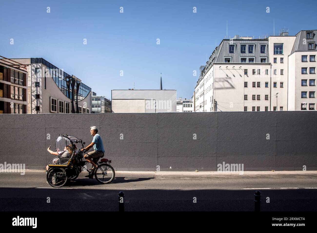 Ein Rikscha-Fahrer mit Touristen fährt an einem Bauzaun in der Nähe des Kölner Doms vorbei. ein Rikscha-Fahrer mit Touristen faehrt an einem Bauzaun Stockfoto