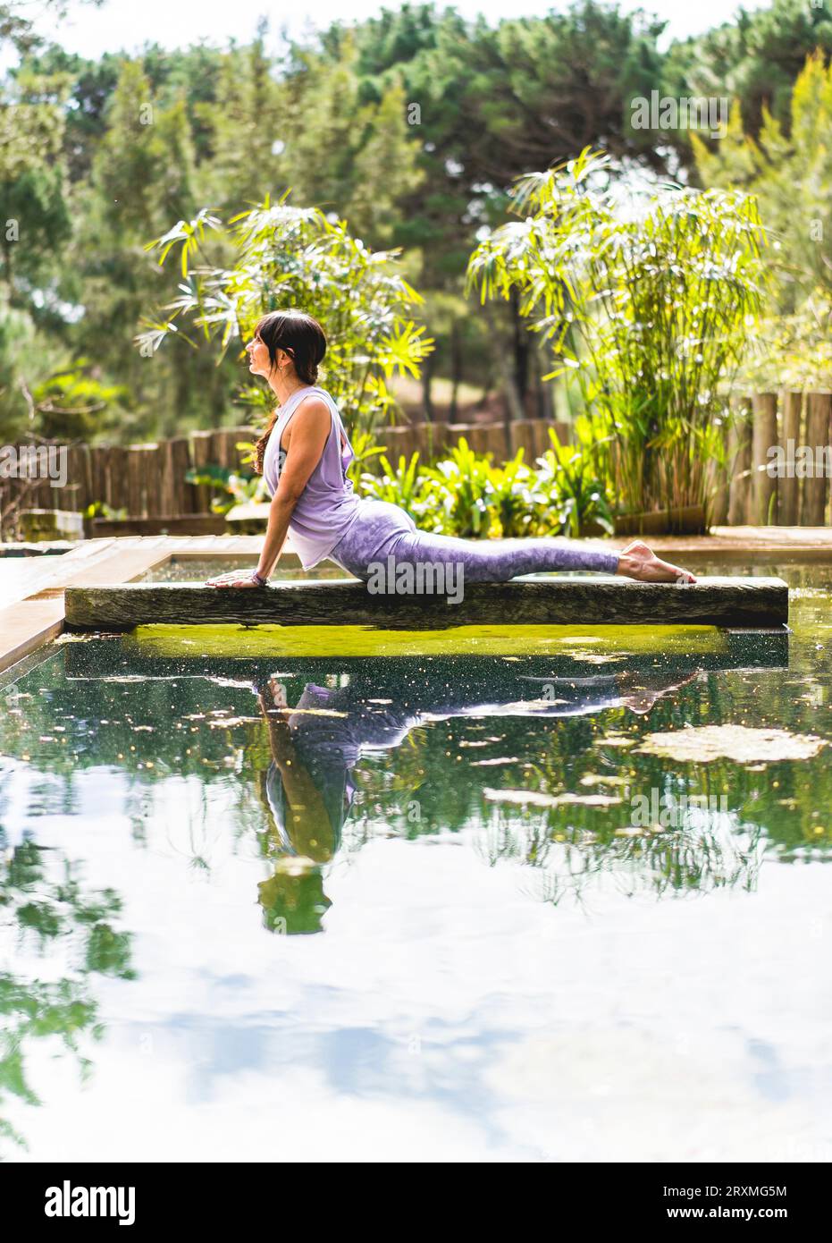 Frau, die Yoga praktiziert, liegt in der Cobra-Pose (Bhujangasana-Übung) draußen. Vertikale Aufnahme. Stockfoto