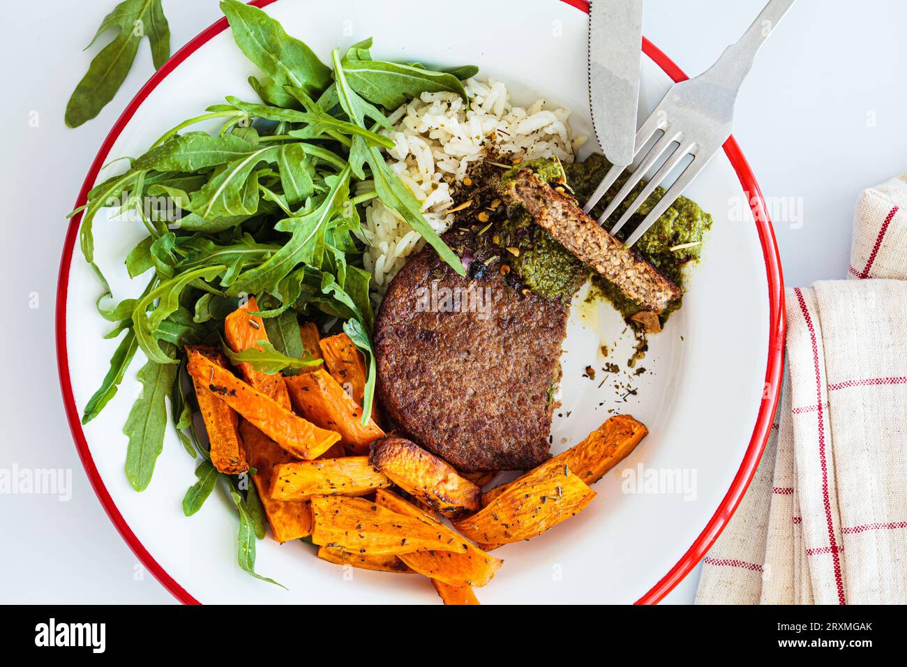 Veganes Fleischschnitzel mit Pesto, gebackenen Süßkartoffelspalten, Reis und Salat, weißer Hintergrund, Draufsicht. Stockfoto