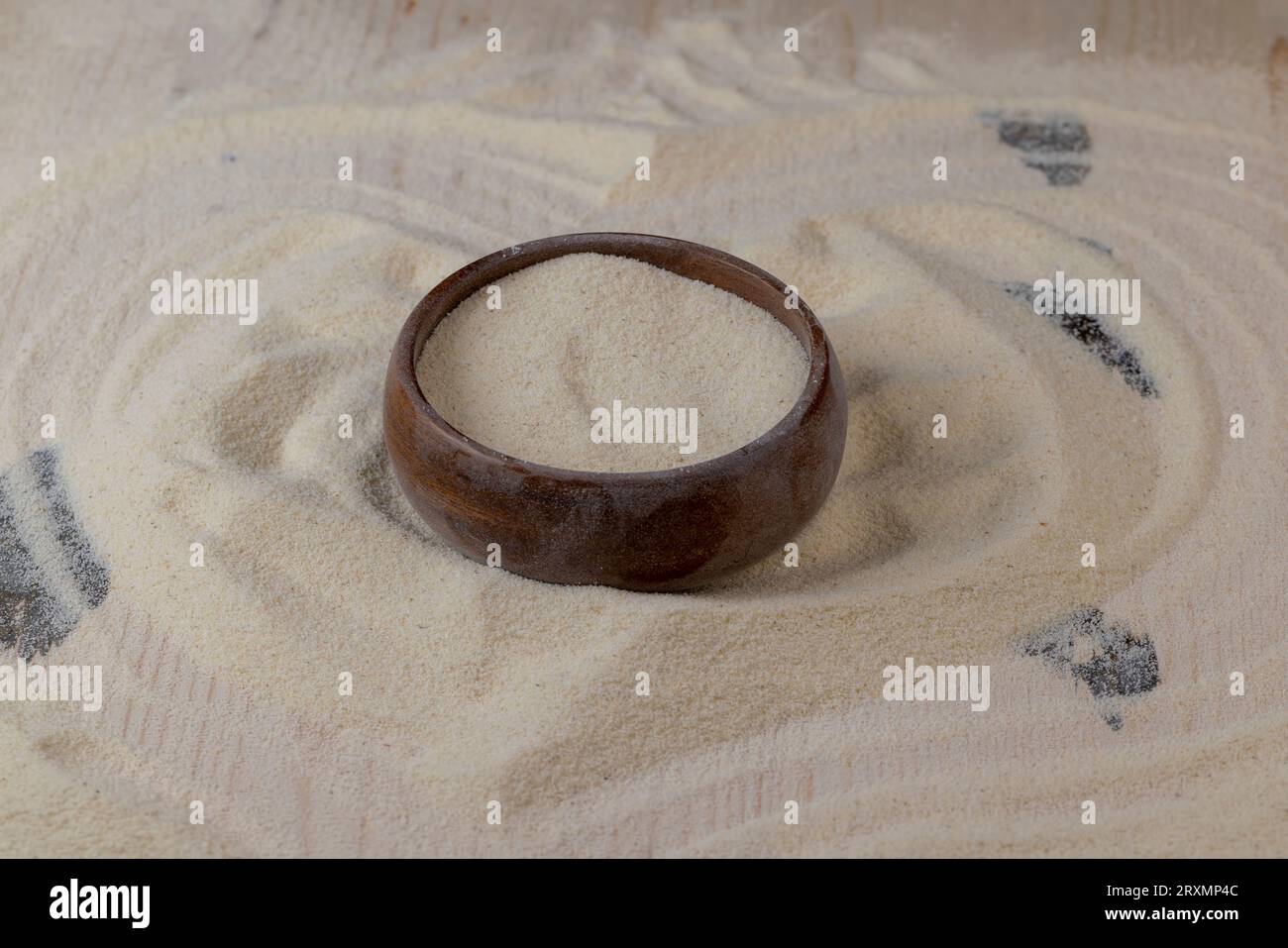 Grieß in eine runde Holzschüssel gegossen, fertig zum Kochen, einfacher Grieß mittlerer Qualität in einer Holzschüssel Stockfoto
