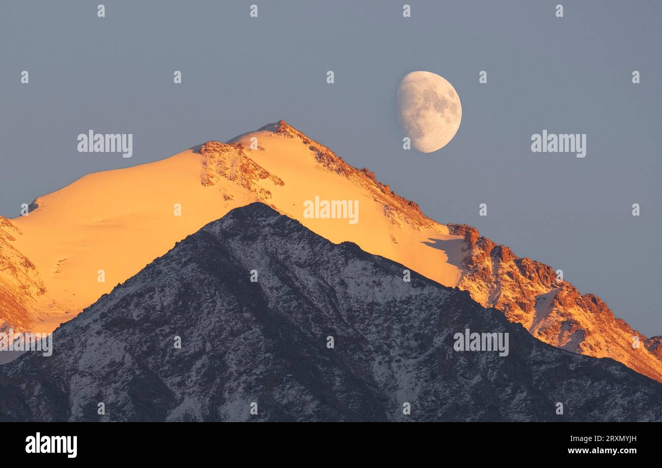 Berglandschaft mit fast Vollmond. Soviet Peak und Skalisty Peak in der Großen Almaty-Schlucht in Kasachstan, Alatau Range in Tien Shan Stockfoto