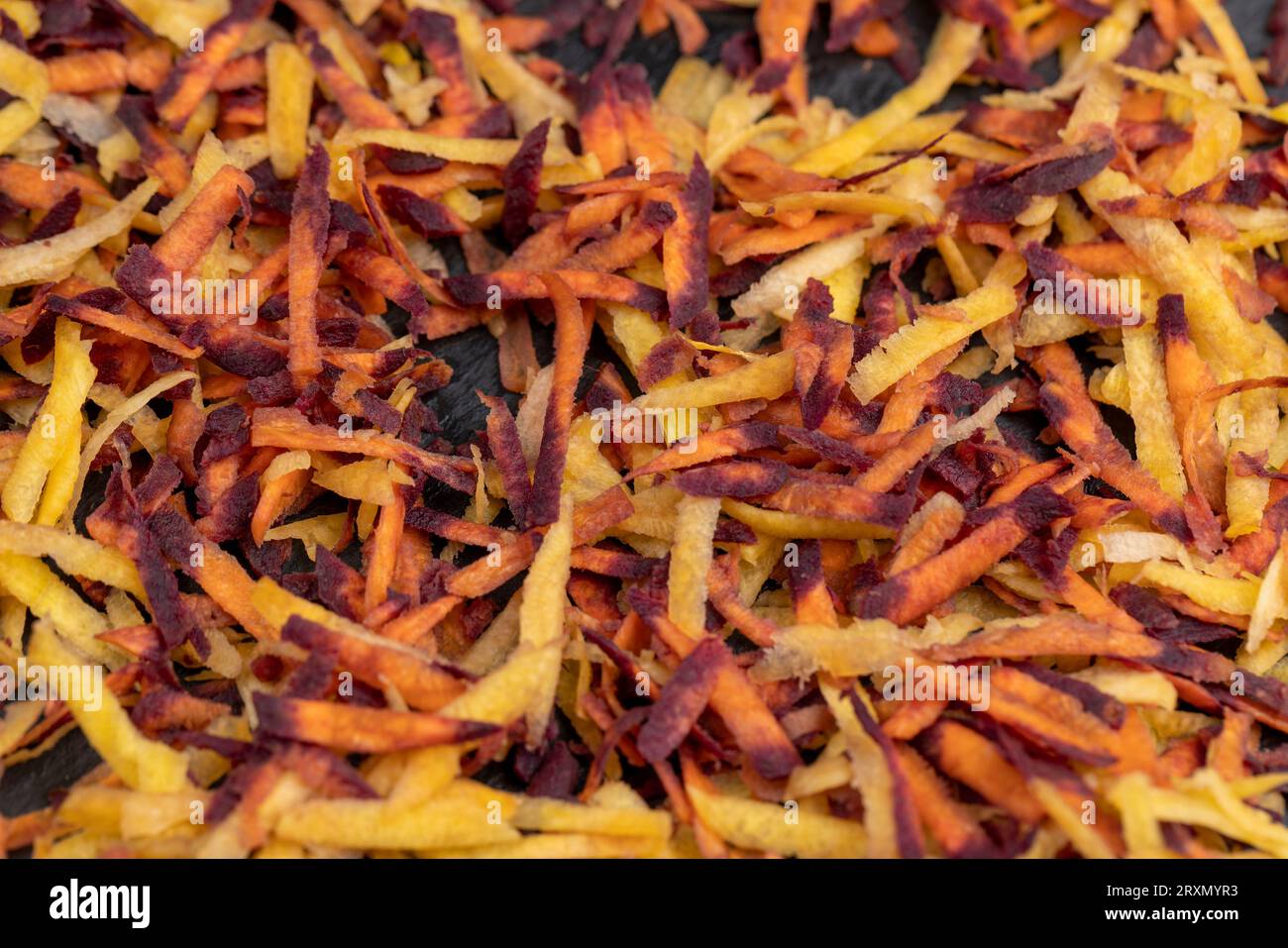 In der Küche in dünne Scheiben von rot-orangefarbenen Karotten geschnitten, mehrere von Schmutz gereinigt und gewaschene Karotten in Stücke geraspelt auf einer Reibe Stockfoto