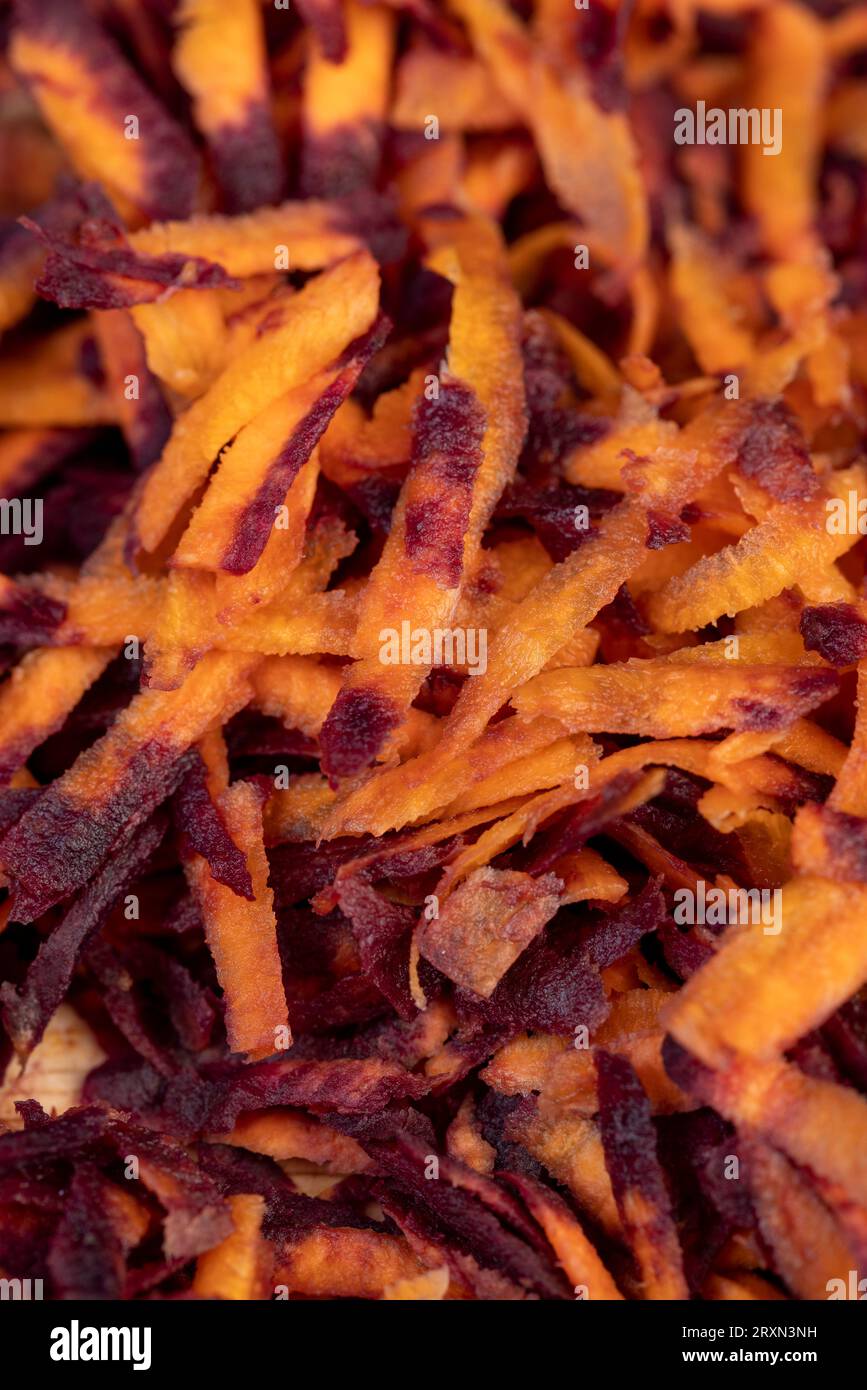 In der Küche in dünne Scheiben von rot-orangefarbenen Karotten geschnitten, mehrere von Schmutz gereinigt und gewaschene Karotten in Stücke geraspelt auf einer Reibe Stockfoto