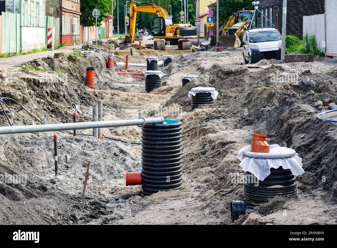 Blick auf den Straßenumbau mit einem breiten Graben, ersetzt Kanalisation und Wasserleitungen und viele Kunststoff-Inspektionsbrunnen Stockfoto