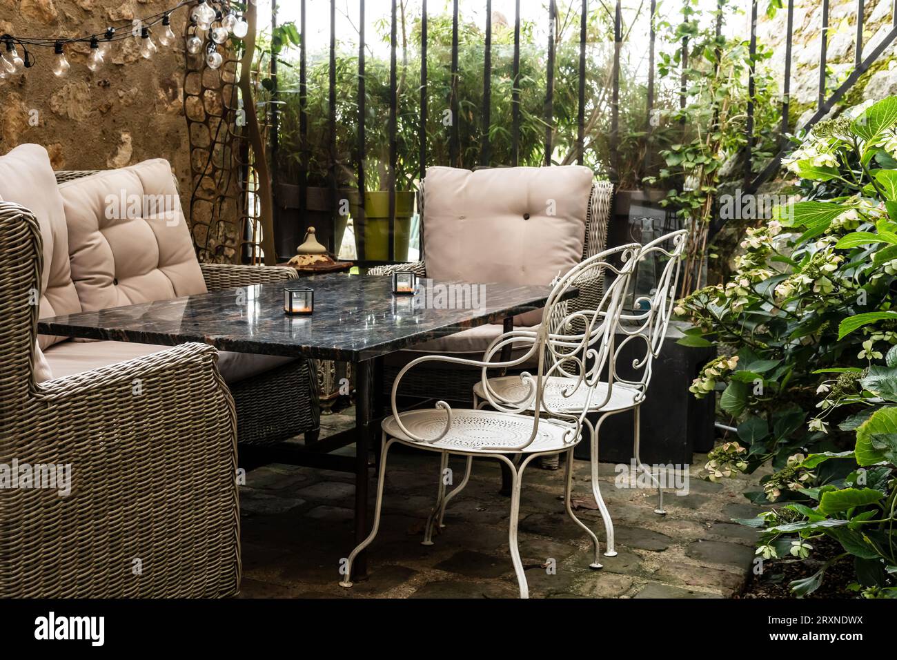 Gartenmöbel in der Nähe eines alten Hauses, umgeben von Pflanzen und Blumen, Freizeitaktivitäten und ruhiges Lifestyle-Konzept Stockfoto