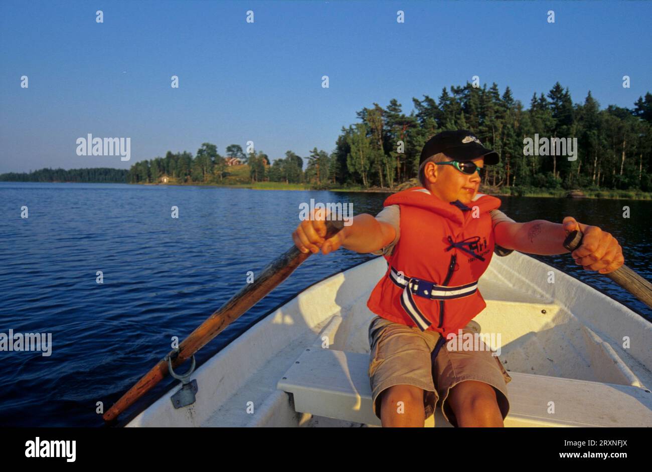 Kleiner Junge mit Sonnenbrille und Baseballmütze in einem Ruderboot auf dem See, Schwimmweste, 8, 9, 10, 11, 12 Jahre alt Stockfoto