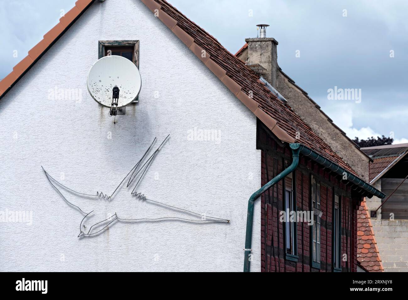 Hausfassade mit Satellitenantenne, dekoriert mit einer aus Draht gebogenen Schwalbe, Nidda, Vogelsberg, Wetteraukreis, Hessen, Deutschland Stockfoto