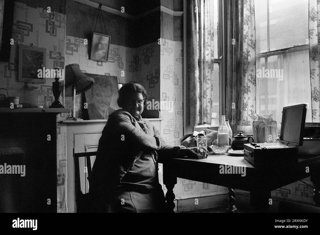 Ältere Dame saß im vorderen Raum ihres viktorianischen Hauses, das auf den Abriss während der Räumung des Slums von St Ann's, Nottingham, England, wartet. Stockfoto