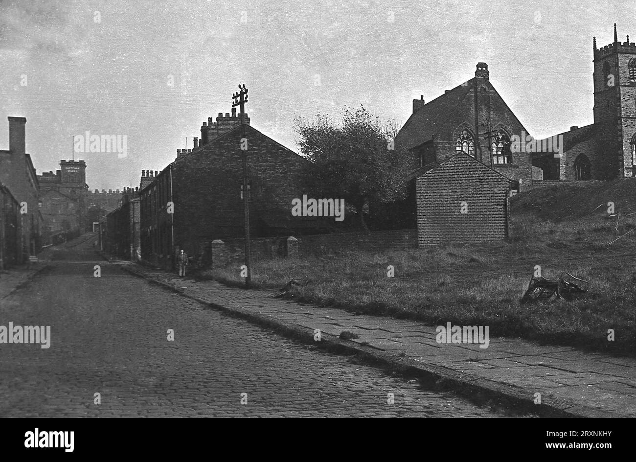 1960er Jahre, historisch, sehen Sie eine Kopfsteinpflasterstraße mit kleinen Terrassenhäusern und links oben auf der Straße die lokale Textilfabrik Hartford Works in Parsons St, Oldham, Lancashire, England, Großbritannien. Stockfoto