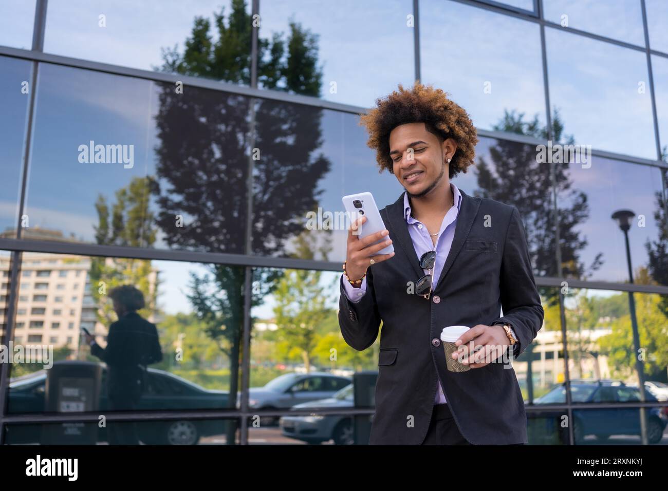 Cooler Geschäftsmann, der das Handy während einer Kaffeepause im Freien benutzt Stockfoto