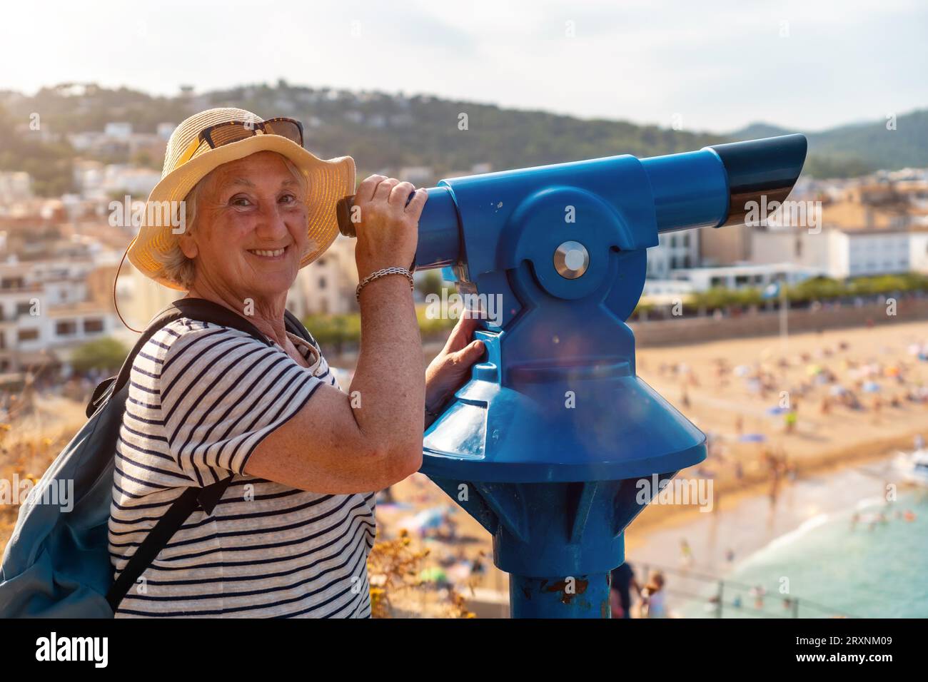 Seitenansicht einer glücklichen älteren Frau, die durch ein Münzfernglas schaut und lächelt Stockfoto