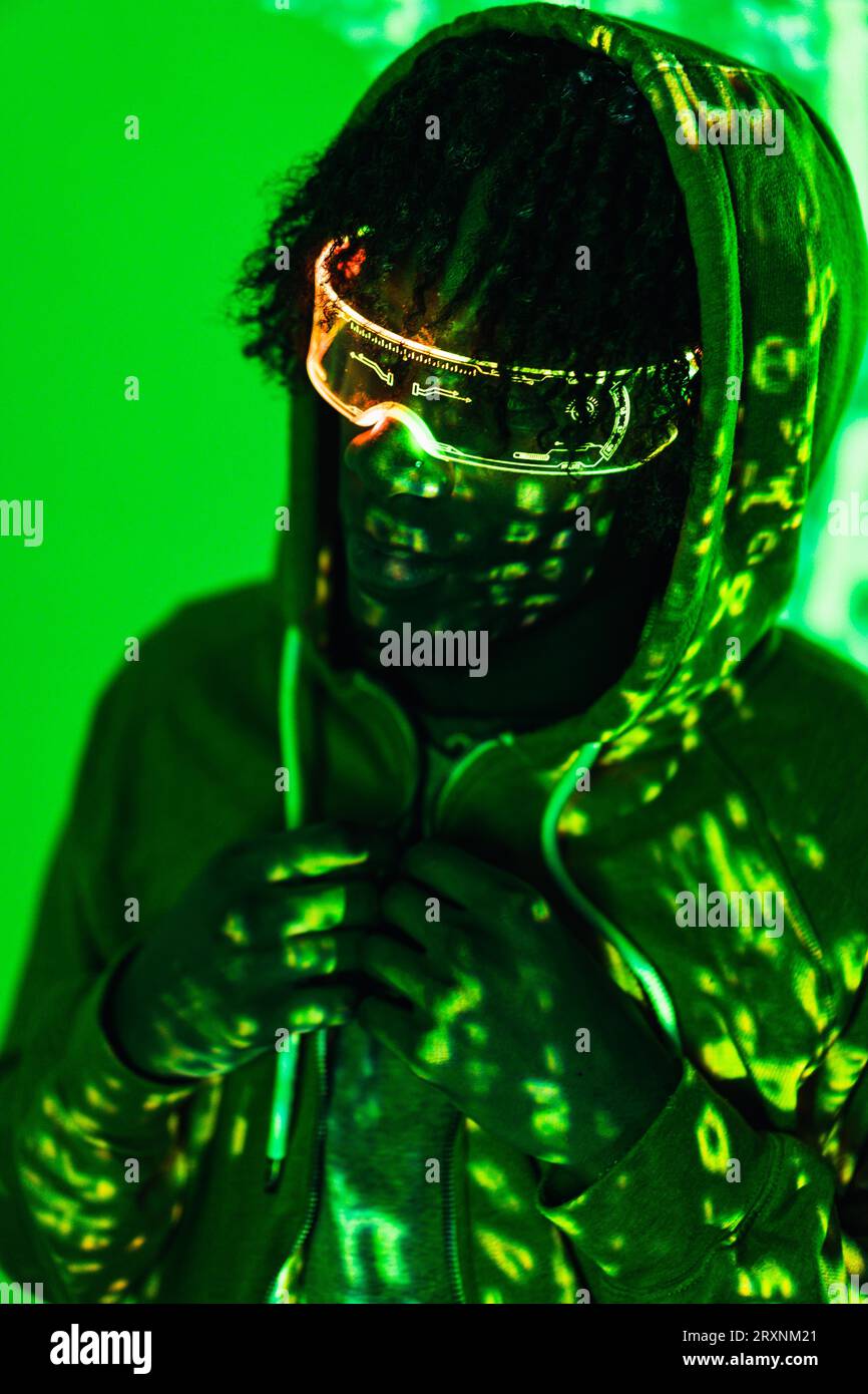 Vertikales Foto mit grünen Neonlichtern der Projektion auf einen Mann mit futuristischer Brille Stockfoto