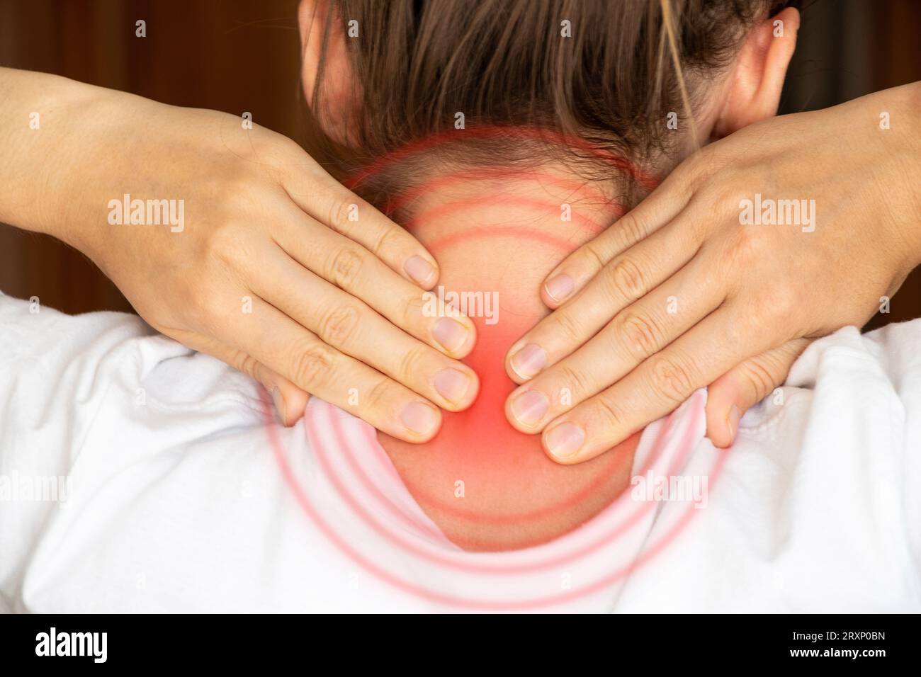 Ein Mädchen hält ihre Hände zu Hause hinter dem Hals, Halsschmerzen, akute Nackenschmerzen Stockfoto