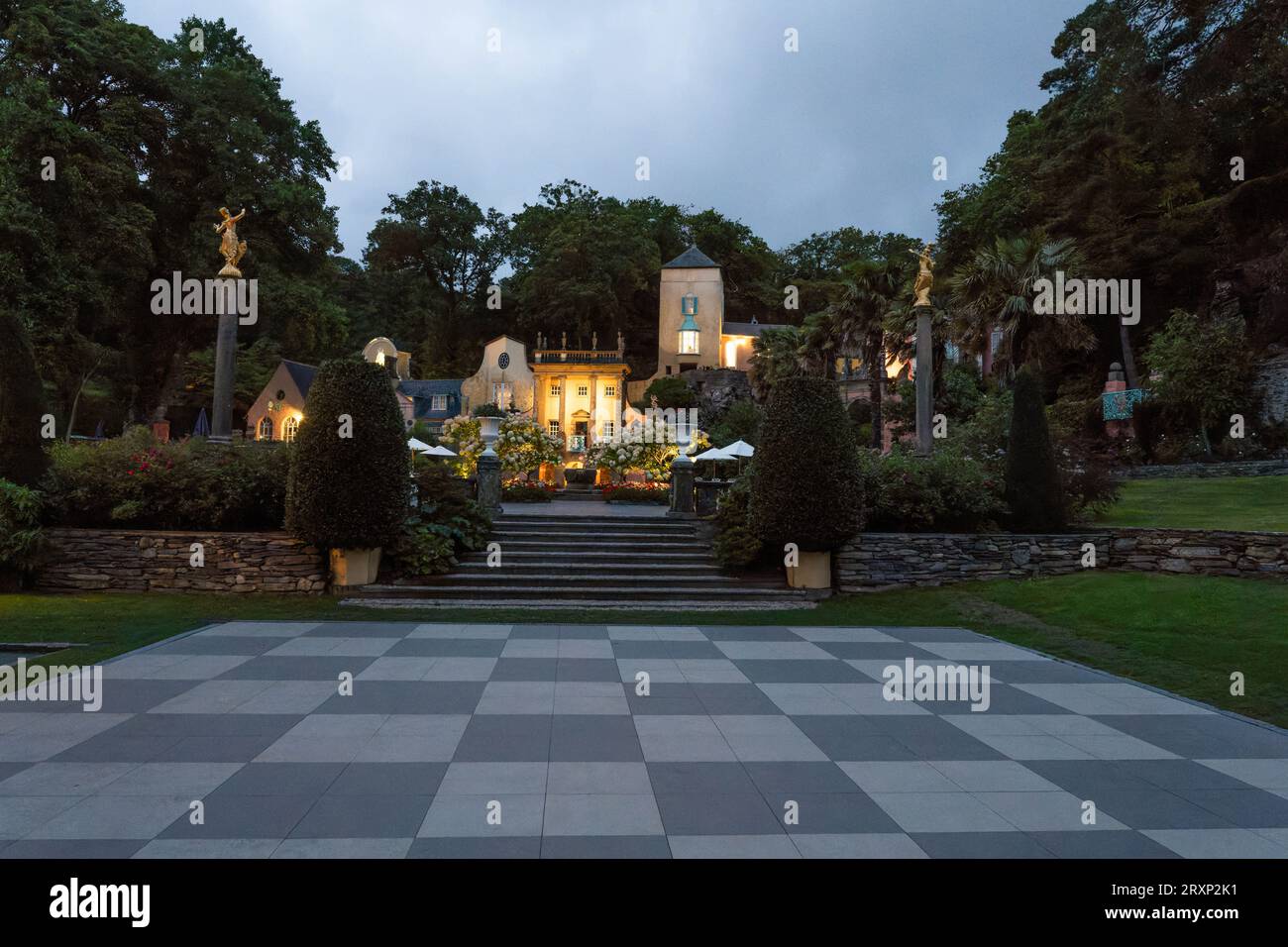 Schachbrettplatz im Dorf Portmeirion mit beleuchteten Gebäuden im italienischen Stil in der Abenddämmerung Stockfoto