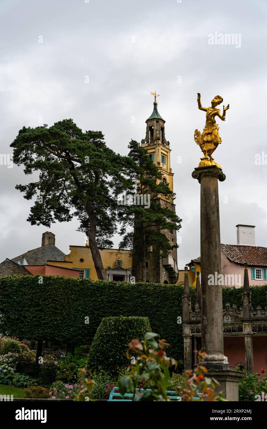 Goldene Statue auf Säule mit bunten Gebäuden und Glockenturm im berühmten walisischen Dorf Stockfoto