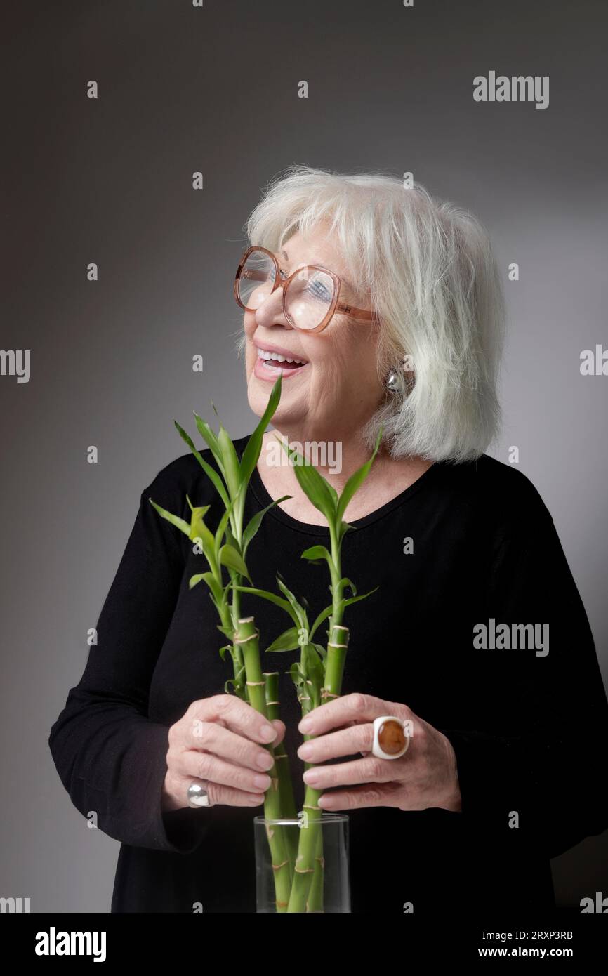 Ältere Frau, die mit Bambuspflanzen dekoriert ist Stockfoto