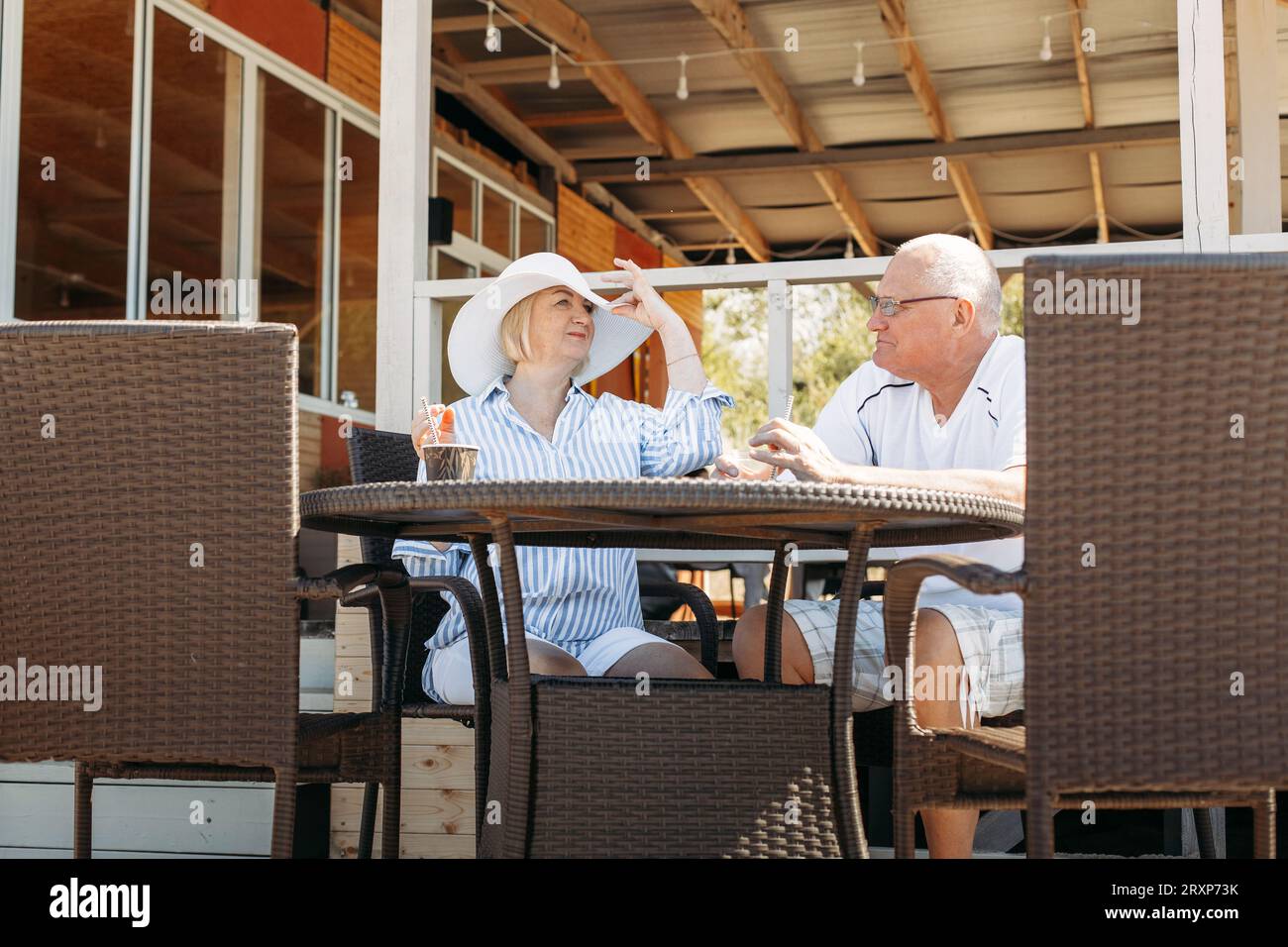 Glückliches reifes Paar mittleren Alters, das redet, Frau zeigt ihren Hut, flirtet. Auf ein Date in einem Café. Stockfoto