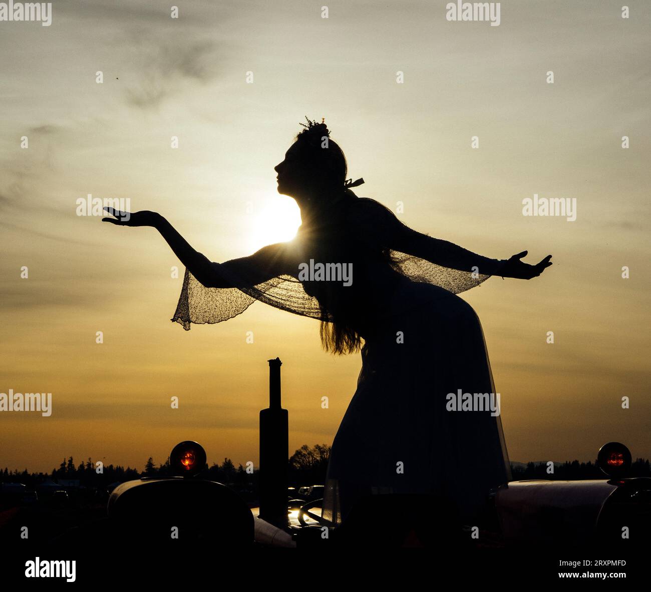 Silhouette einer Frau, die gegen die untergehende Sonne steht, mit dem Korb in der Hand Stockfoto