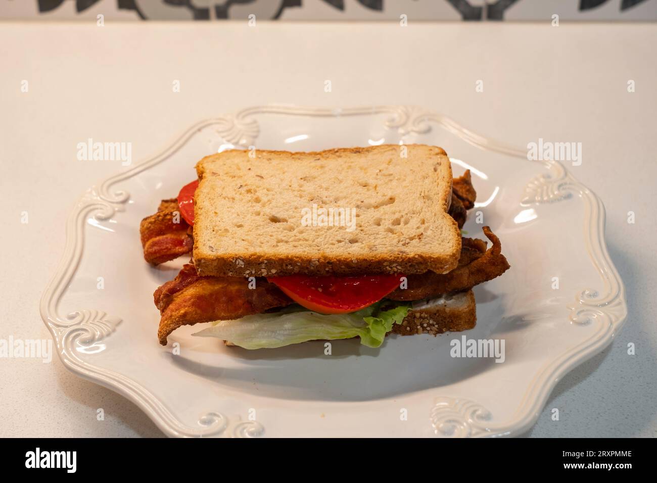 BLT, ein Sandwich mit Speck, Tomaten und Salat, das mit Hafernußbrot auf einem weißen Teller serviert wird. USA. Stockfoto