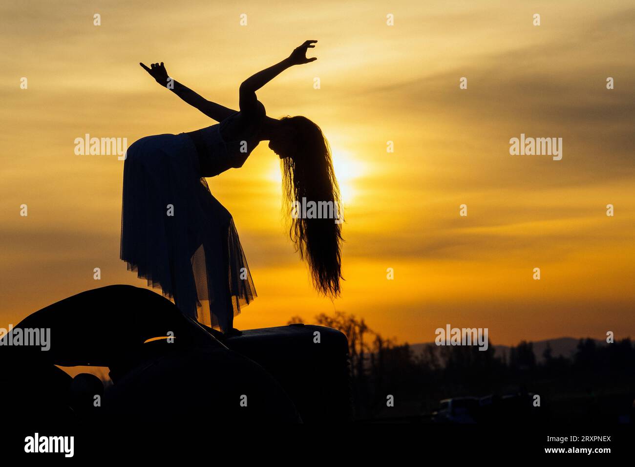 Silhouette einer langhaarigen Frau, die gegen die untergehende Sonne posiert Stockfoto