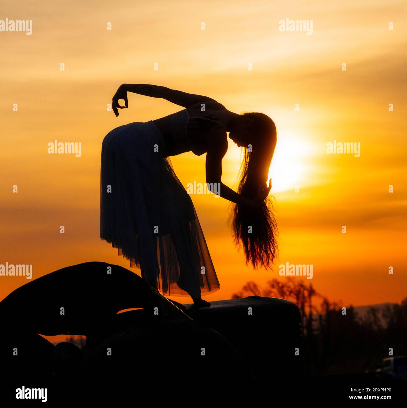 Silhouette einer langhaarigen Frau, die gegen die untergehende Sonne posiert Stockfoto