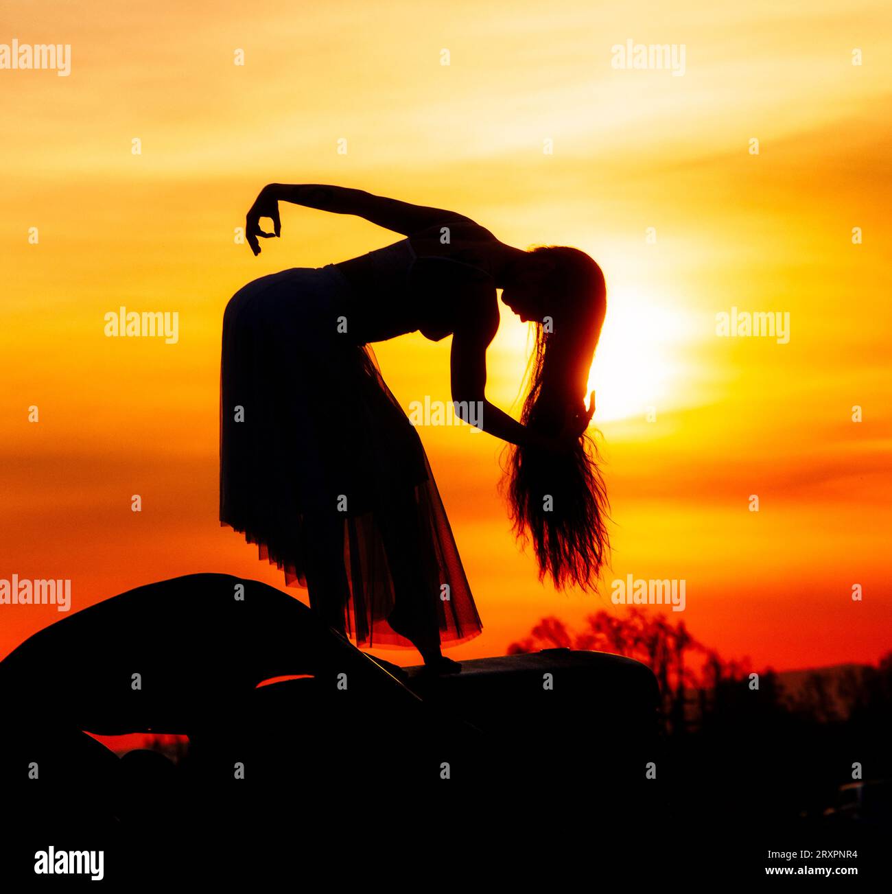 Silhouette einer langhaarigen Frau, die gegen die untergehende Sonne posiert Stockfoto