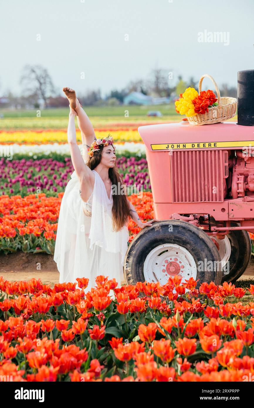 Frau, die einen bunten Regenschirm hält und sich auf dem rostigen Traktor teilt Stockfoto