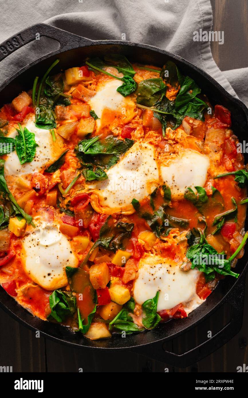 Ratatouille Brunch Skillet mit Eiern und Spinat: Auberginen, Zucchini, Paprika und Tomateneintopf in einer gusseisernen Skillet Stockfoto