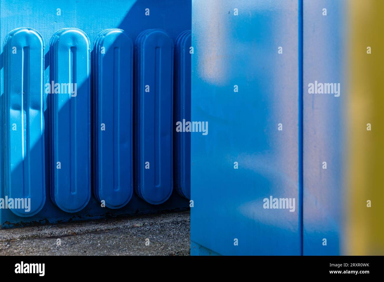 Blaue und gelbe Wände in einer urbanen Szene auf Granville Island, Vancouver, Kanada. Helle und schattige Bereiche in der Sommersonne. Stockfoto