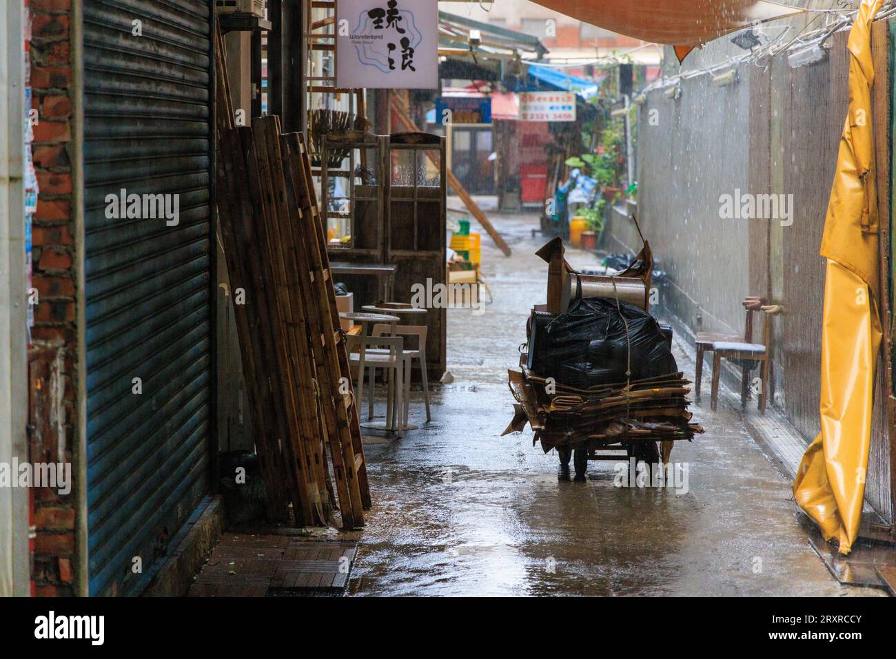 Harter Regen fällt auf den verlassenen Sammelwagen aus Pappe in der Gasse Stockfoto