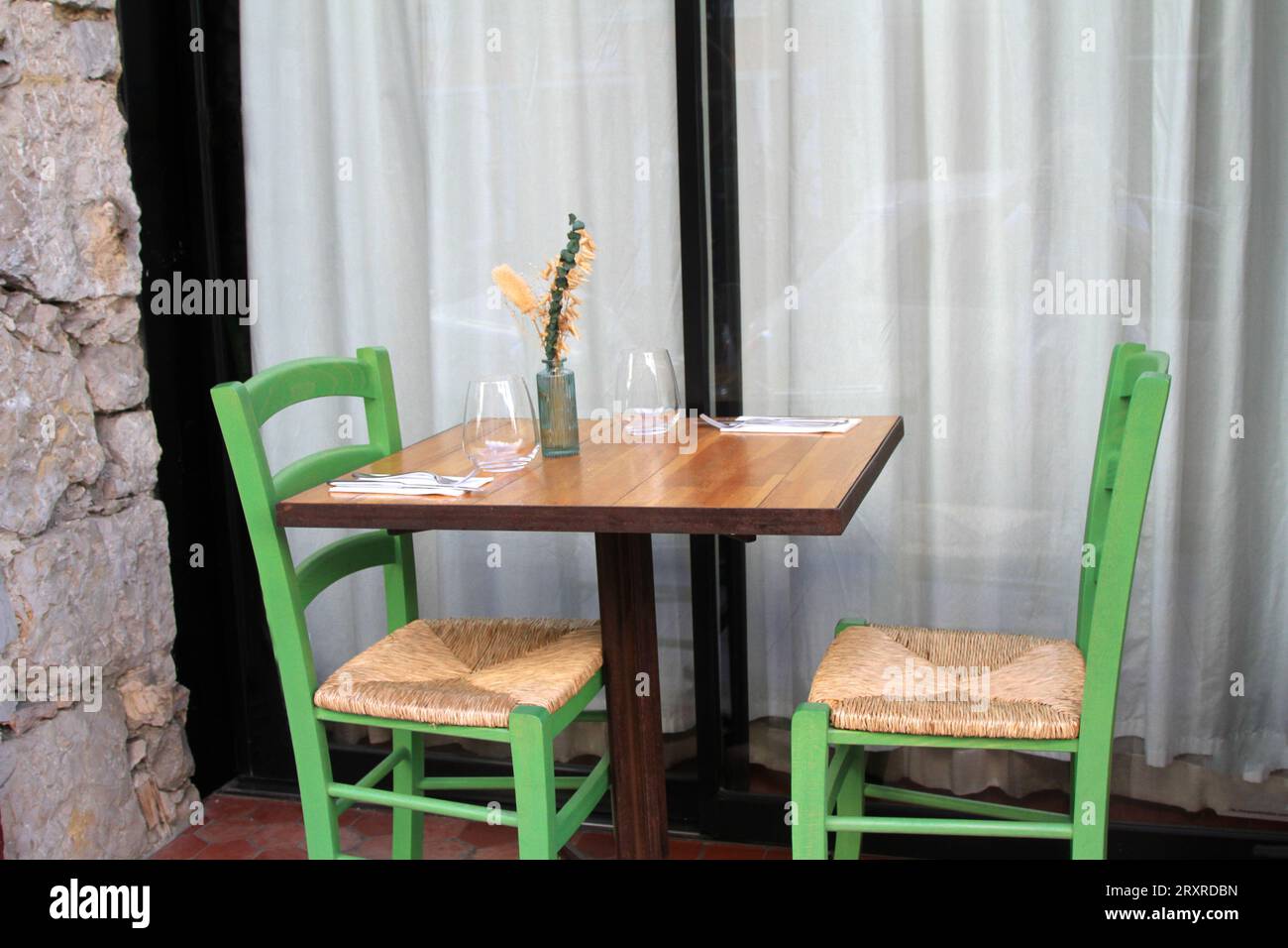 Tisch im Freien mit zwei grünen Stühlen und Rattansitzen Stockfoto