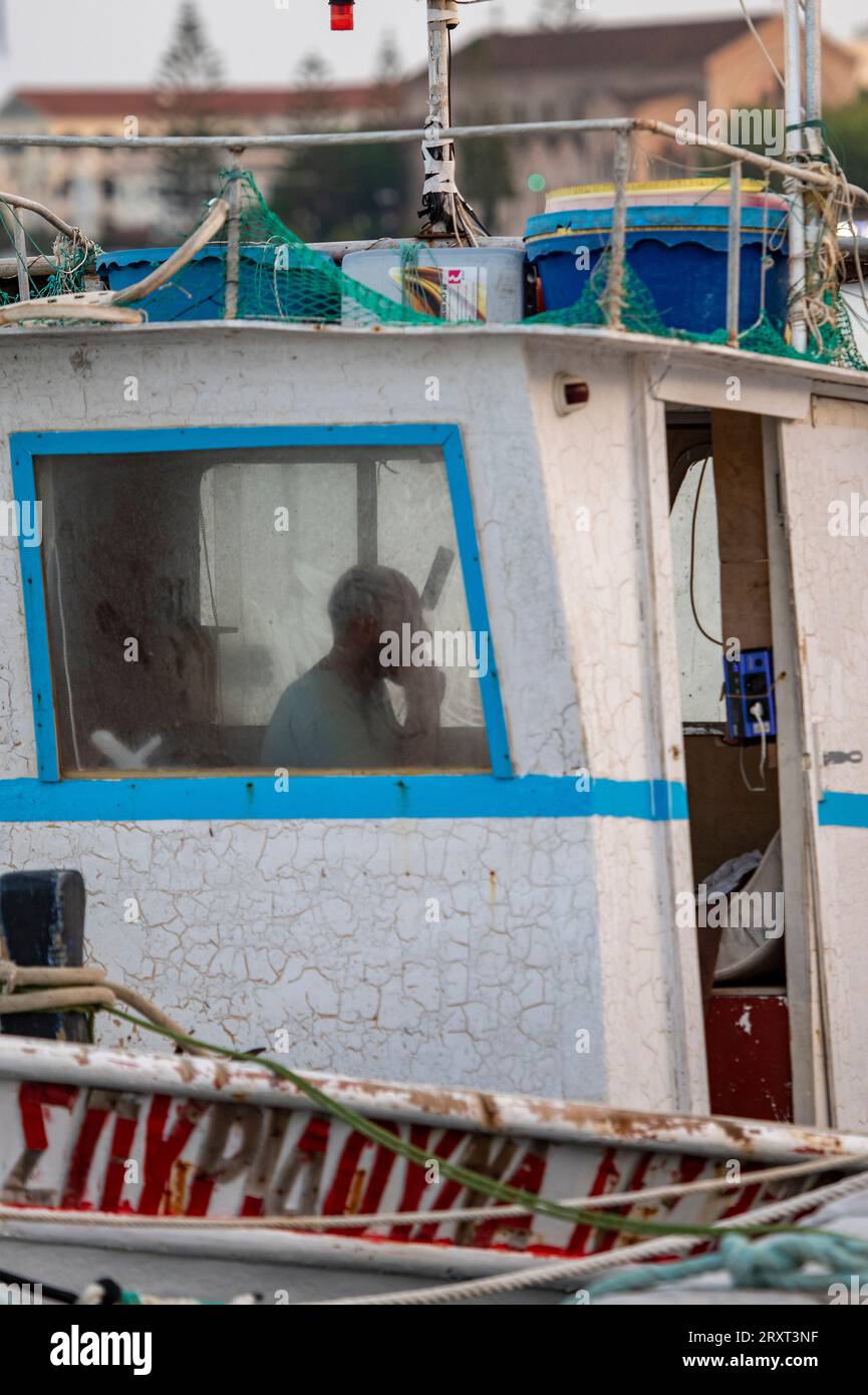 griechischer Fischer, der allein im Rollhaus eines alten Holzfischbootes auf der griechischen Insel zante oder zakynthos sitzt Stockfoto