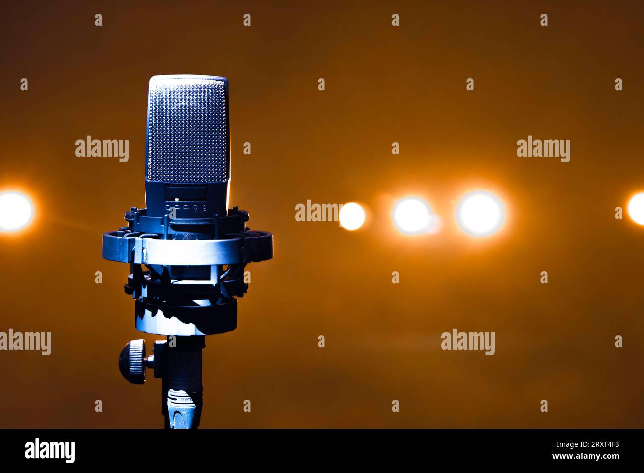 Ein Mikrofon auf einem Ständer auf einer Bühne mit Spotlights im Hintergrund Stockfoto