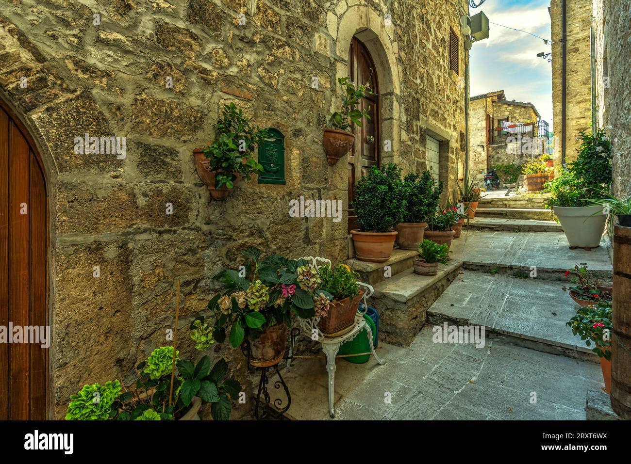 Gassen und Treppen zwischen Steinhäusern und bunten Blumenkästen im mittelalterlichen Dorf Castel Trosino. Ascoli Piceno, Region Marken, Italien, EU Stockfoto