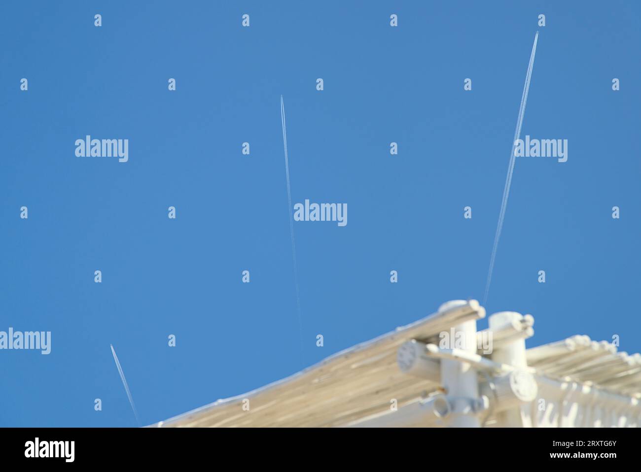 Spuren von drei Flugzeugen, die an einem klaren blauen Himmel in verschiedene Richtungen fliegen Stockfoto