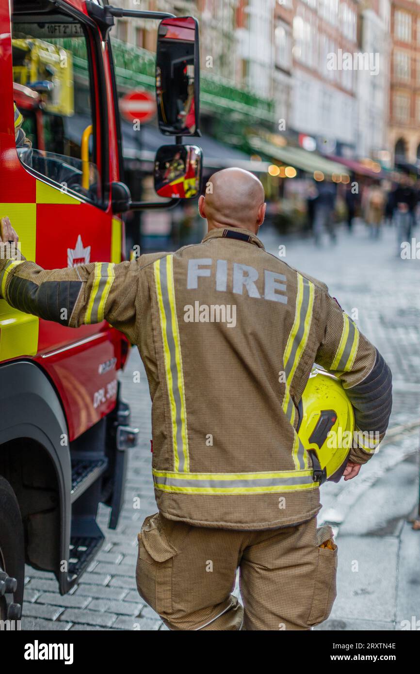 Ein kahlköpfiger Feuerwehrmann am Tatort eines Vorfalls in London. Stockfoto