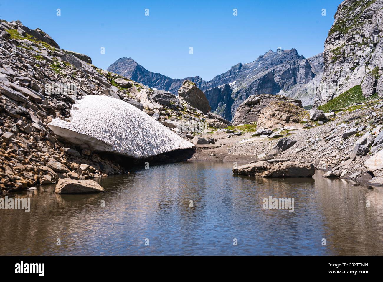 Überreste eines Schneefeldes in den Alpen, das in einen See auf einem Alpenpass verschmilzt, die Alpen, Piemont (Piemont) Norditalien, Europa Stockfoto